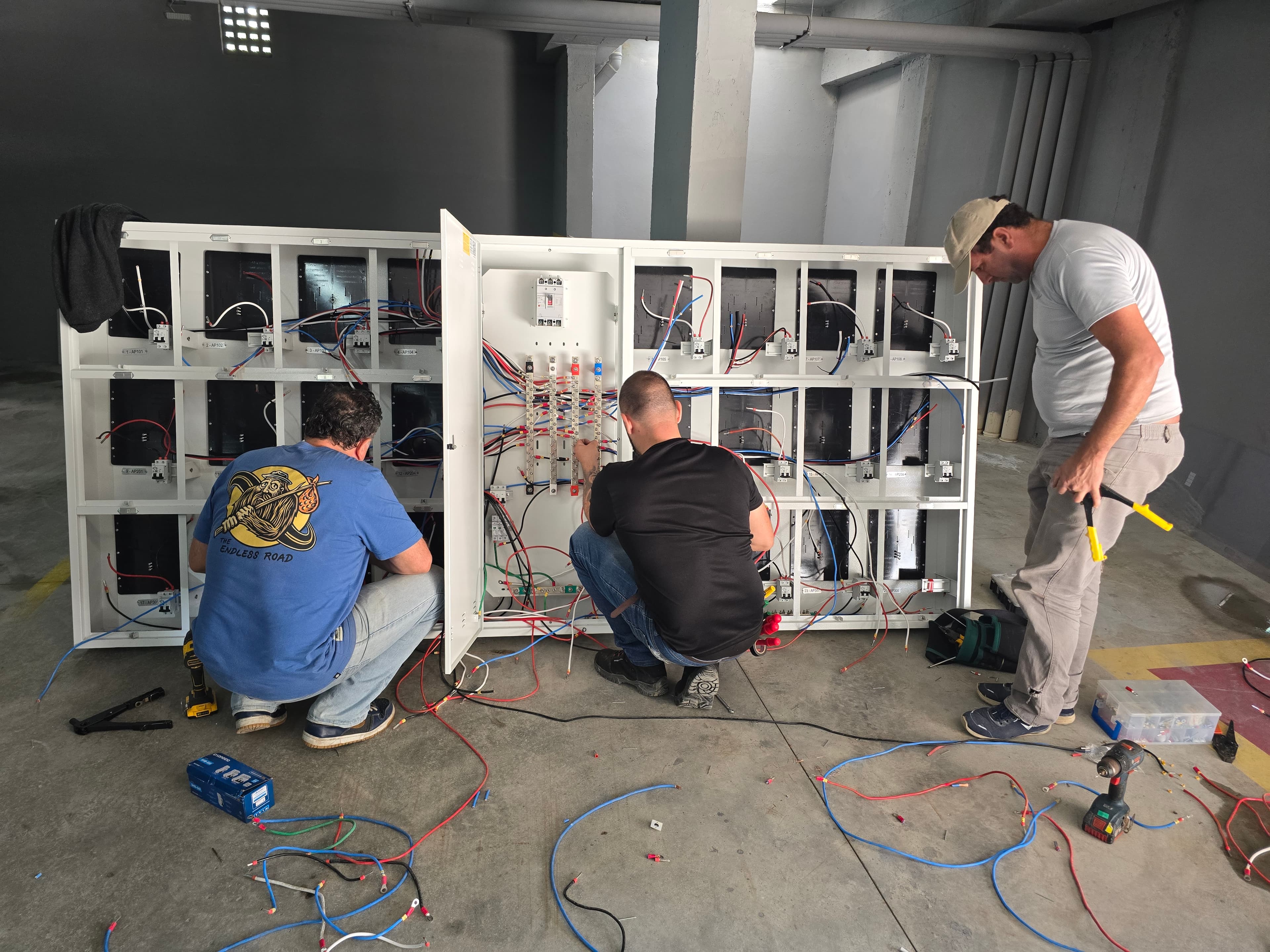 Técnicos instalando painel de carregadores para veículos elétricos em garagem