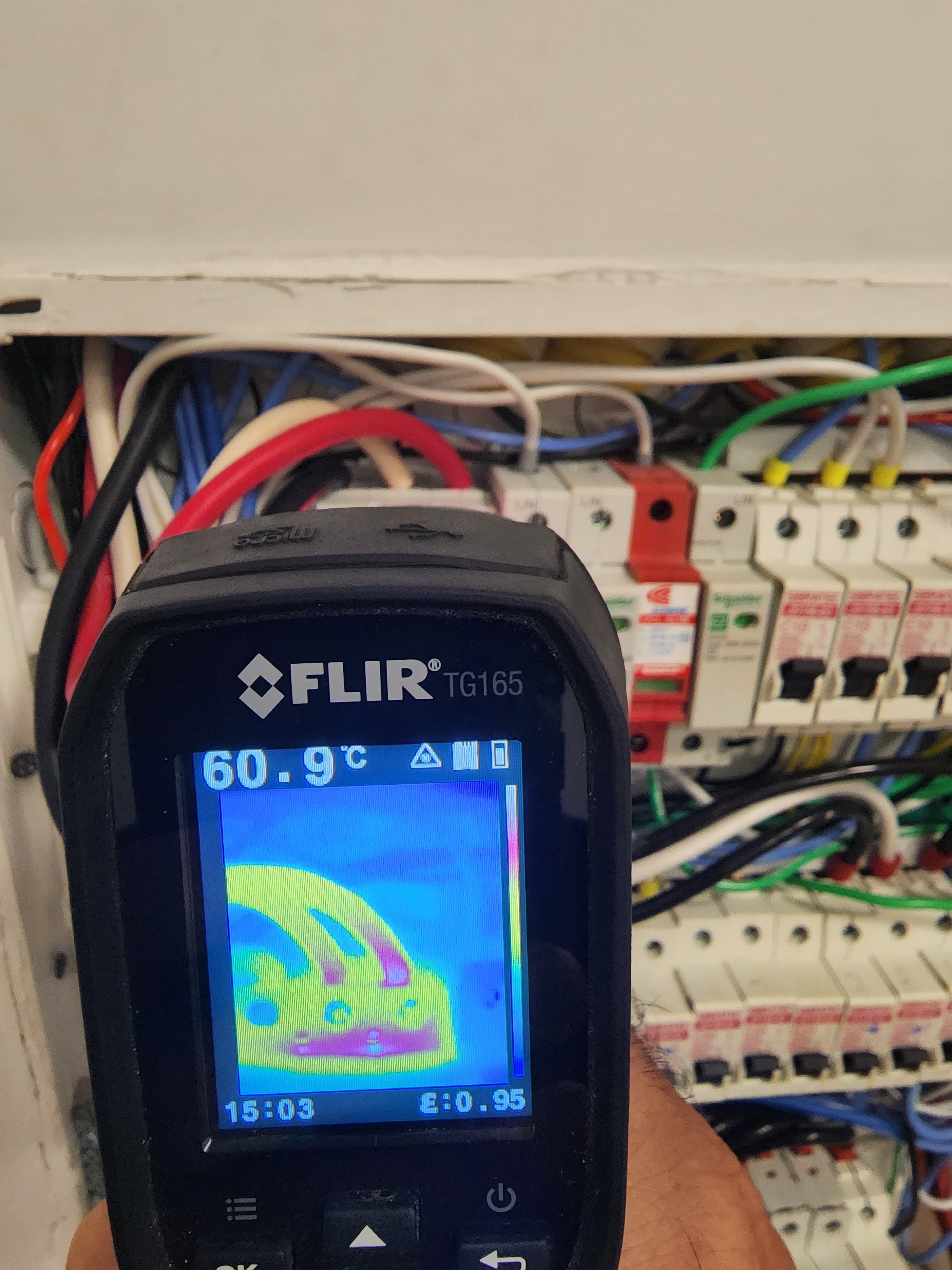 Câmera termográfica FLIR apontada para quadro elétrico mostrando 60,9°C — auditoria elétrica ISR Engenharia